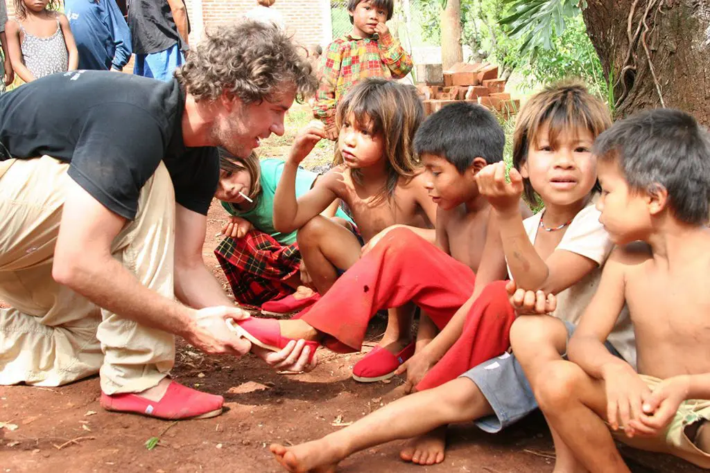 A photo of Tom's founder Blake Mycoskie distributing shoes