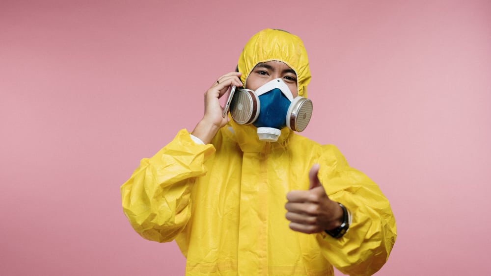 Person in protective suit talking on phone with thumbs up - How to Start a Business While Quarantining