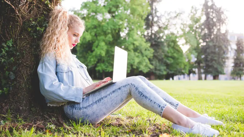 Woman using laptop on grass reading personalised content