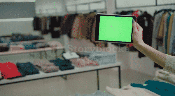 Hand holding tablet with green screen at a fashion store